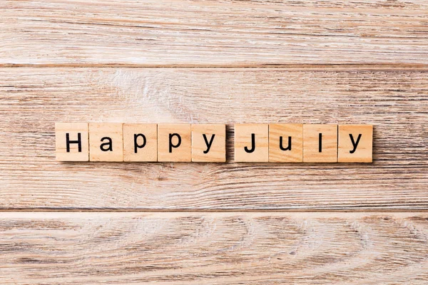 Happy july word written on wood block. Happy july text on table, concept.