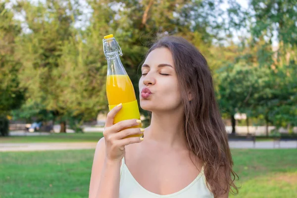 Söt flicka njuter av sin promenad i parken med en flaska färsk kall juice — Stockfoto