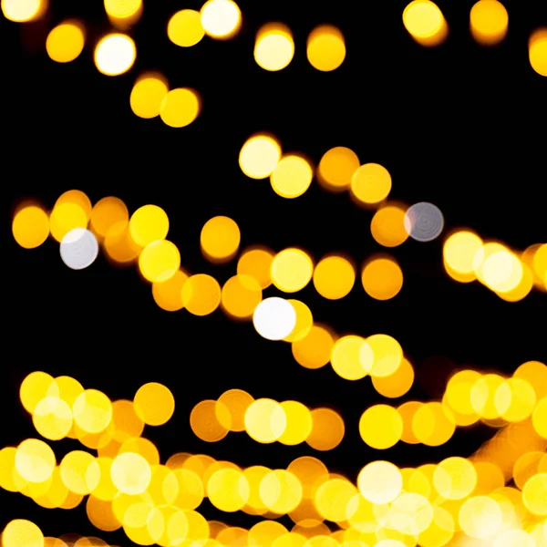 Holiday glowing gold backdrop. defocused and blurred many round yellow light on Christmas black background — Stock Photo, Image