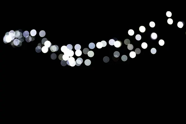 Abstraktes Bokeh weißer Stadtlichter auf schwarzem Hintergrund. defokussiert und verschwommen viel rundes Licht — Stockfoto