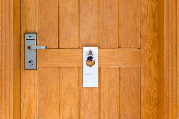 Por favor no molestar signo en la puerta de madera cerrada de la habitación de hotel —  Fotos de Stock