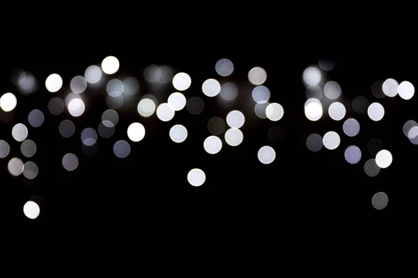 Bokeh white lights on black background, defocused and blurred many round light on background