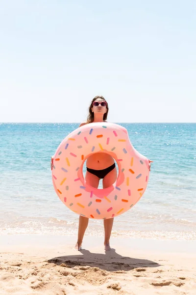 Mulher que joga com anel inflável. Menina relaxante em rosa inflável na praia. Férias de verão e conceito de férias em uma ilha tropical — Fotografia de Stock