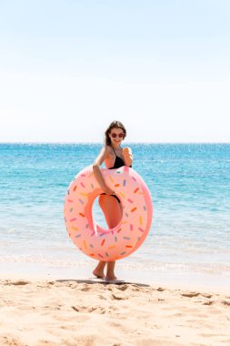 şişme bir donut halkası ile oynarken sahilde mutlu kadın. Yaz tatilleri ve tatil konsepti