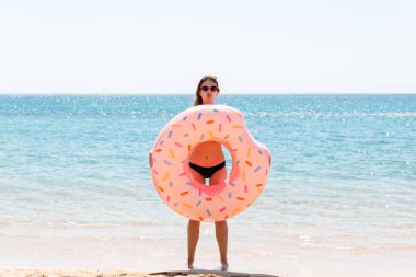 şişme bir donut halkası ile oynarken sahilde mutlu kadın. Yaz tatilleri ve tatil konsepti