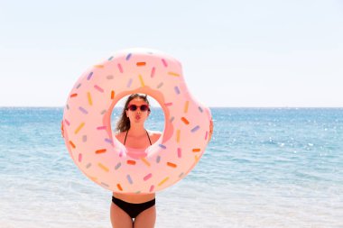 Güzel çılgın kadın rahatlatıcı ve deniz plajında şişme halka ile oynuyor. Yaz tatilleri ve tatil konsepti