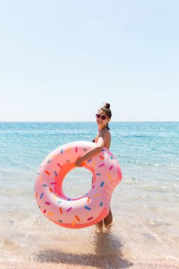 Bir kadın denize girer. Sahilde şişme halka üzerinde rahatlatıcı kız. Yaz tatilleri ve tatil konsepti