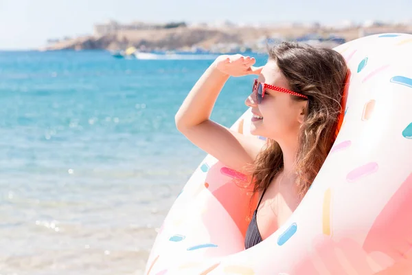Retrato de una chica feliz mirando a través de anillo inflable estancia en la playa del mar. Vacaciones de verano y concepto de vacaciones —  Fotos de Stock