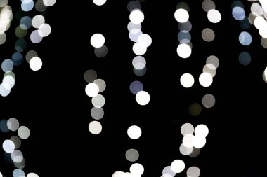 Siyah arka plan üzerine odaklanmamış soyut beyaz bokeh. ufuk ve bulanık çok yuvarlak ışık