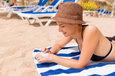 Plajda güneşlenmeden önce eldeki güneş kremi koyan kadının yakın çekim