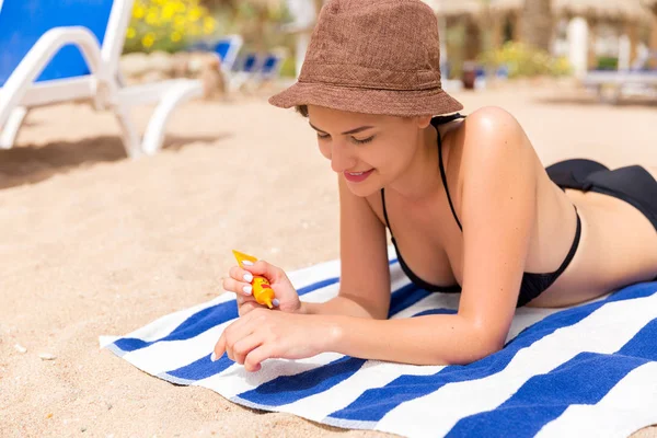 Kadın elleri güneş kremi şişesinden güneş kremi sürüyor.