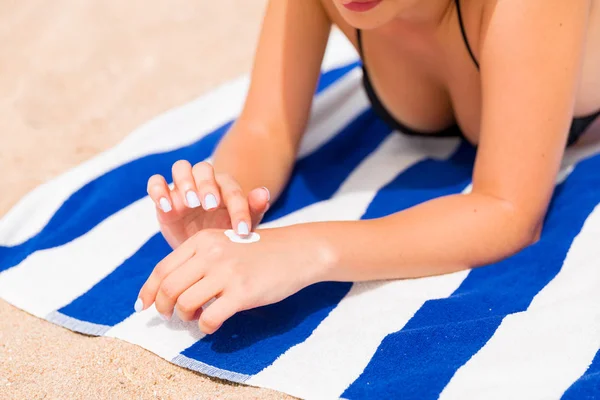 在海滩晒日光浴前，妇女将防晒霜放在手上的特写镜头 — 图库照片