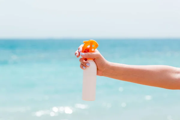 Image recadrée de la main d'une femme tenant un spray solaire sur la plage — Photo