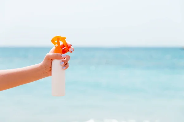 Przycięty obraz dłoni kobiety trzymającej spray z filtrem przeciwsłonecznym na plaży — Zdjęcie stockowe