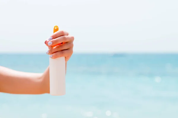 Abgeschnittenes Bild der Hand einer Frau mit Sonnenschutzspray am Strand — Stockfoto