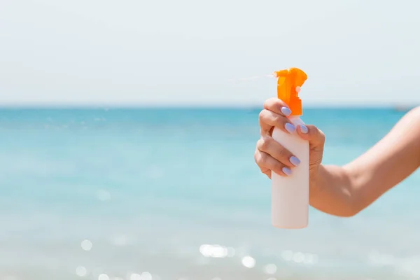 Przycięty obraz dłoni kobiety trzymającej spray z filtrem przeciwsłonecznym na plaży — Zdjęcie stockowe