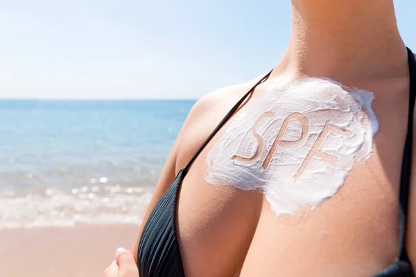 Word spf aus Sonnencreme Lotion auf der Brust der Frau über Meeresgrund gemacht. Sonnenschutzfaktor-Konzept — Stockfoto