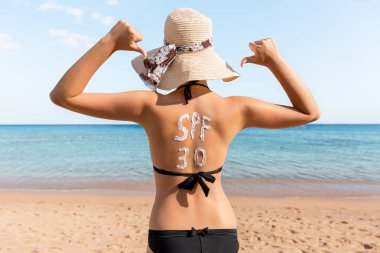 Spf 30 kelime plajda rahatlatıcı kadının sırtına güneş kremi ile çizilir