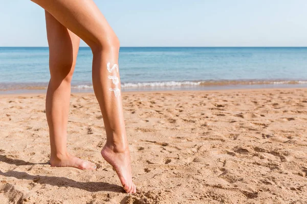 Frauenbeine mit einem Wort aus Sonnencreme am Strand. Sonnenschutzfaktor-Konzept — Stockfoto