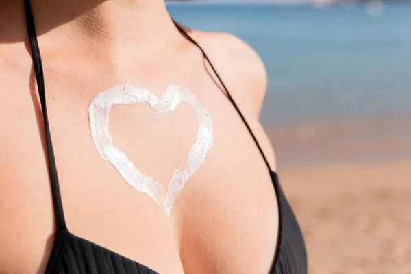 Gebräunte Frau mit herzförmiger Sonnencreme auf der Brust am Meeresgrund — Stockfoto