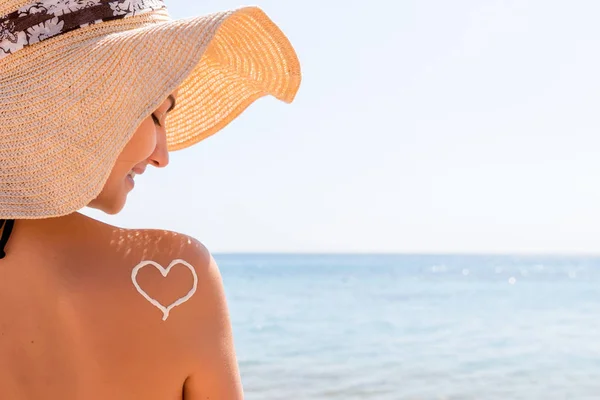 Herz aus Sonnencreme wird am Strand auf die Schulter der Frau gezeichnet — Stockfoto