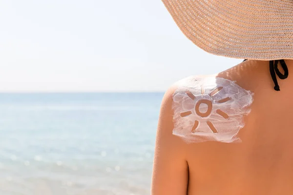 Loción protector solar en forma de sol en el hombro de la mujer bronceada — Foto de Stock
