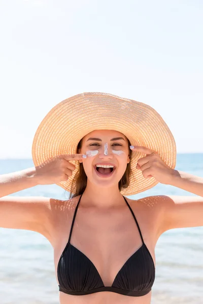 Mulher sorridente de chapéu está aplicando protetor solar em seu rosto. Estilo indiano — Fotografia de Stock
