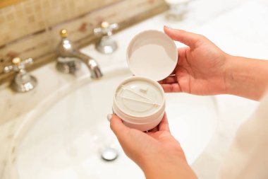 Banyoda hidrojel göz bantlı bir kutu tutan ve açan kadın. Sabah spa konsepti