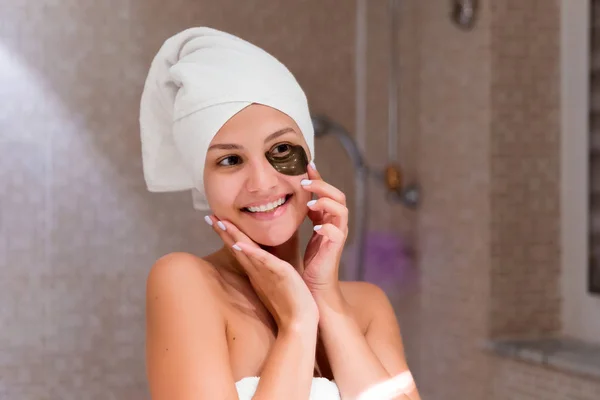 Woman in bathroom applying black eye patches. Skin care and spa morning concept — Stock Photo, Image