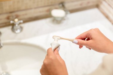 Banyoda diş fırçası üzerinde diş macunu uygulayan çekici kadın el Kırpılmış görüntü. Güzellik sağlıklı yaşam sabah kavramı