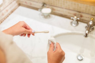 Banyoda diş fırçası üzerinde diş macunu uygulayan çekici kadın el Kırpılmış görüntü. Güzellik sağlıklı yaşam sabah kavramı