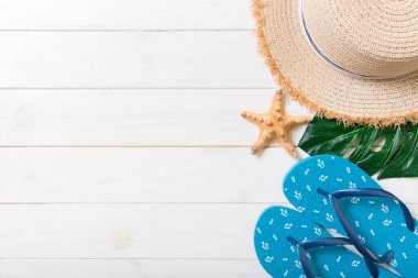 Hasır şapka, yeşil yaprak, mavi parmak arası terlik ve denizyıldızı beyaz ahşap bir arka plan üzerinde. kopya alanı ile üst görünüm yaz tatili konsepti