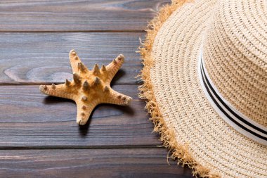 Hasır şapka ve denizyıldızı Koyu ahşap bir arka plan üzerinde. kopya alanı ile üst görünüm yaz tatili konsepti