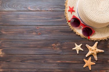 Hasır şapka, güneş gözlüğü ve denizyıldızı koyu ahşap arka plan üzerinde. kopya alanı ile üst görünüm yaz tatili konsepti