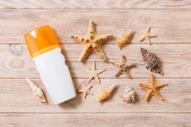 ahşap arka plan üzerinde güneş koruma krem şişe ve deniz kabukları. yaz seyahat tatil düz yatıyordu kavramı
