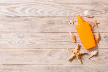 Kopya alanı ile ahşap tahta arka plan üzerinde denizyıldızı ile güneş kremi şişe üst görünümü. yaz seyahat tatil düz yatıyordu kavramı
