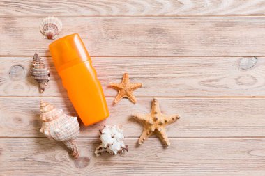 Kopya alanı ile ahşap tahta arka plan üzerinde denizyıldızı ile güneş kremi şişe üst görünümü. yaz seyahat tatil düz yatıyordu kavramı