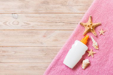 Plaj düz kopyalama alanı ile aksesuarlar yatıyordu. Pembe havlu, denizyıldızı ve ahşap arka planda bir şişe güneş kremi. Yaz tatili konsepti