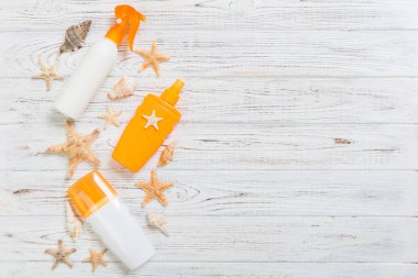 beyaz ahşap tabl üzerinde deniz kabukları ile güneş koruma krem şişeleri