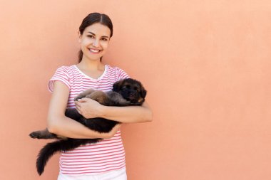 Evde beslenen hayvan köpek turuncu arka planda tutan mutlu genç kadın