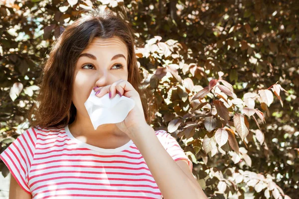 Ung flicka blåser hennes näsa. Ung flicka med allergi i höst park — Stockfoto