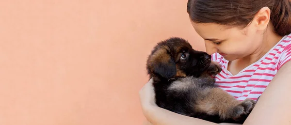 Beautiful woman holding and looking into black puppy's eyes — Stock Photo, Image