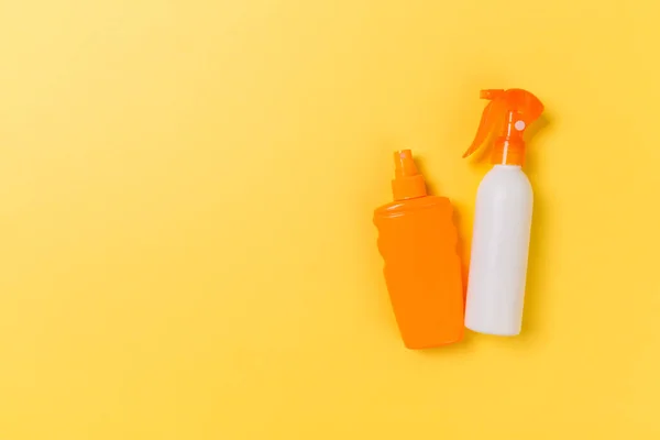 flat lay concept of summer travel vacation. Sunscreen bottle mock up on yellow background top view with copy space