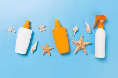 Mavi masa üstü görünümünde deniz kabukları ile güneş kremi şişeler