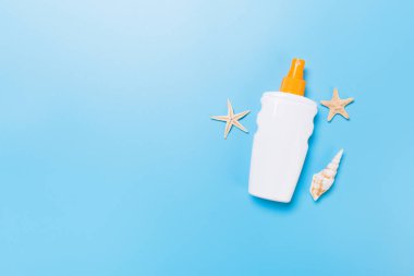 mavi arka plan üzerinde şişelerde denizyıldızı ve deniz kabukları ile güneş kremi, üst görünümü
