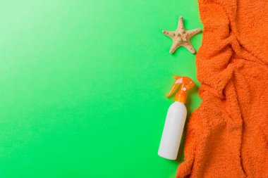 Summer beach flat lay accessories. Sunscreen bottle cream, towel and seashells on colored Background. Travel holiday concept with copy space