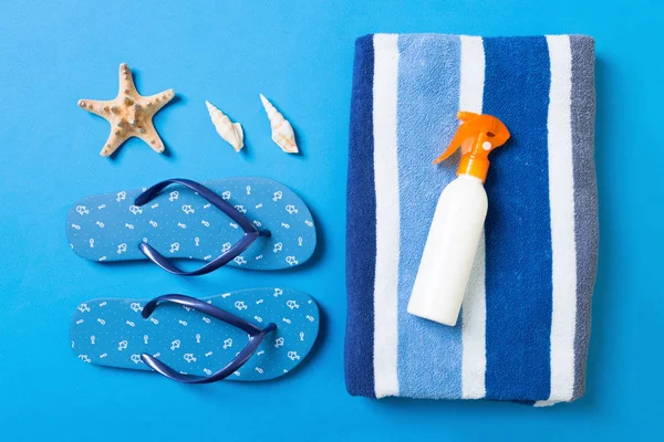Top view of Beach flat lay accessories. sunscreen bottle with seashells, starfish, towel and flip-flop on Colored background with copy space — Stock Photo, Image