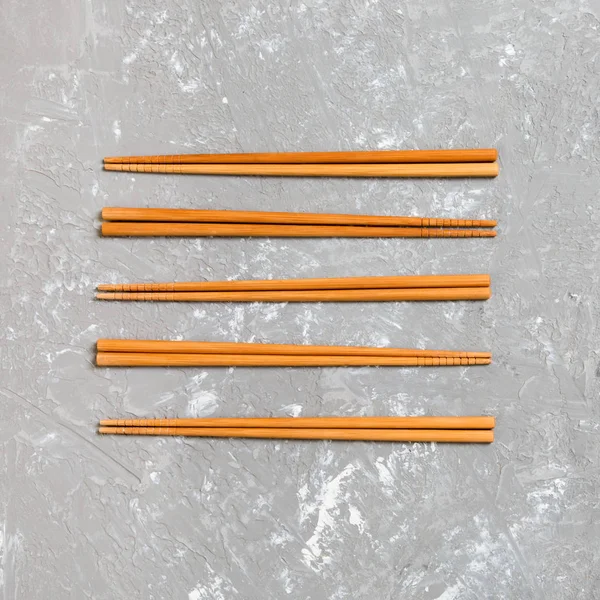 Many bamboo chopsticks on black cement stone background, top view with copy space. a lot of sushi sticks in the form of an ornament — Stock Photo, Image