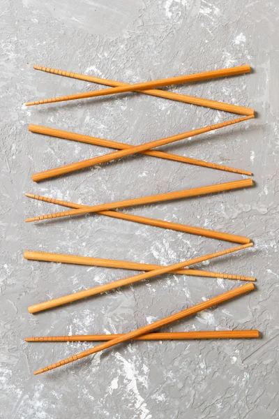 Many bamboo chopsticks on black cement stone background, top view with copy space. a lot of sushi sticks in the form of an ornament — Stock Photo, Image