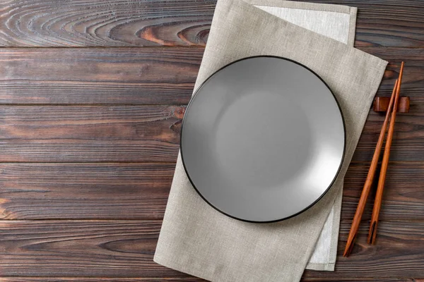 Empty grey round plate with chopsticks for sushi on wooden background. Top view with copy space — Stock Photo, Image